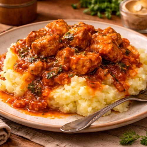 Гуляш из свинины с картофельным пюре в глубокой тарелке крупным планом