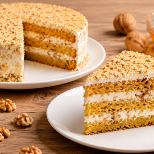 Нежный медовый торт с орехами на тарелке с чашкой чая