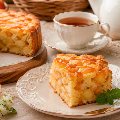 Пышная шарлотка с яблоками на тарелке в разрезе с кусочками яблок