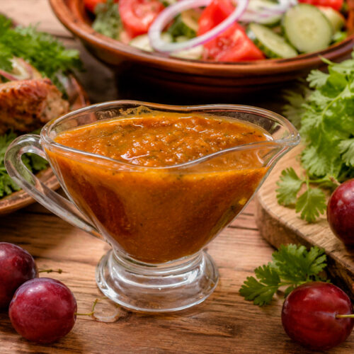 Домашний соус Ткемали к мясу в соуснице на кухонном столе
