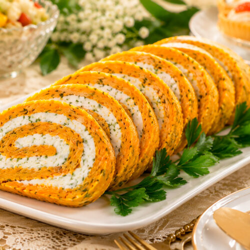 Морковный рулет с сырной начинкой на тарелке с зеленью