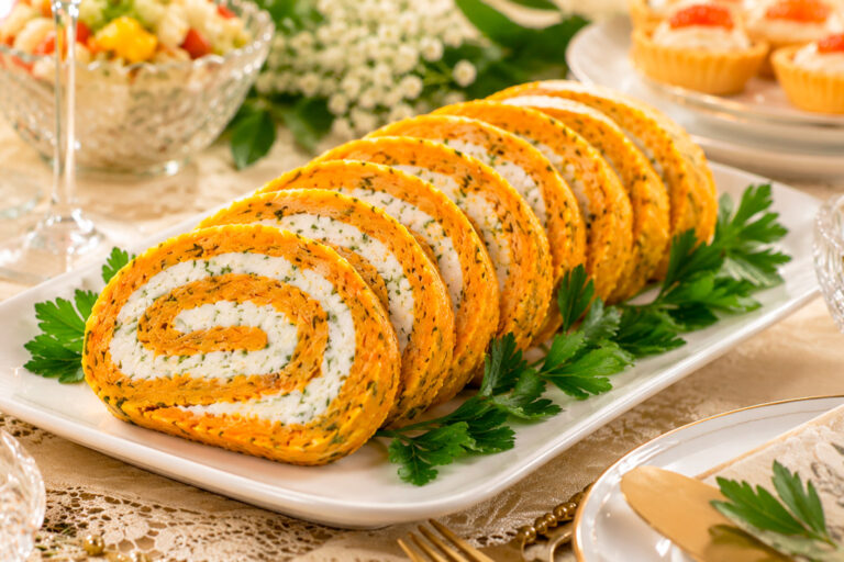 Морковный рулет с сырной начинкой на тарелке с зеленью