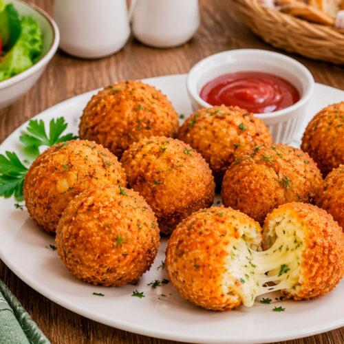Хрустящие картофельные шарики с сыром на столе с соусом для подачи