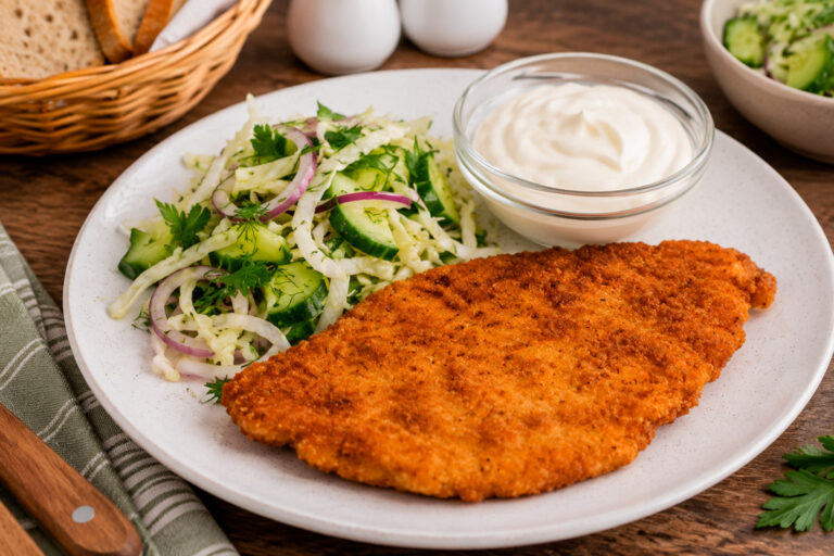 Готовый куриный шницель с хрустящей золотистой панировкой на тарелке.